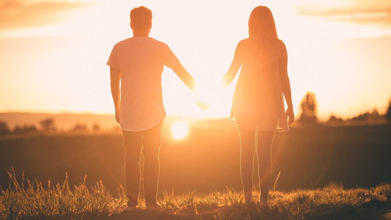 two-people-holding-hands-sunset
